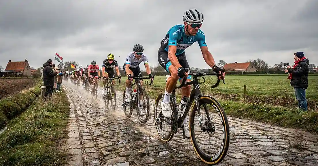 Wielrenners rijden over kasseien in Vlaamse klassieker