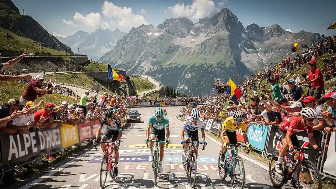 Wielrenners beklimmen steile Alpencol tijdens bergetappe met toeschouwers langs de weg